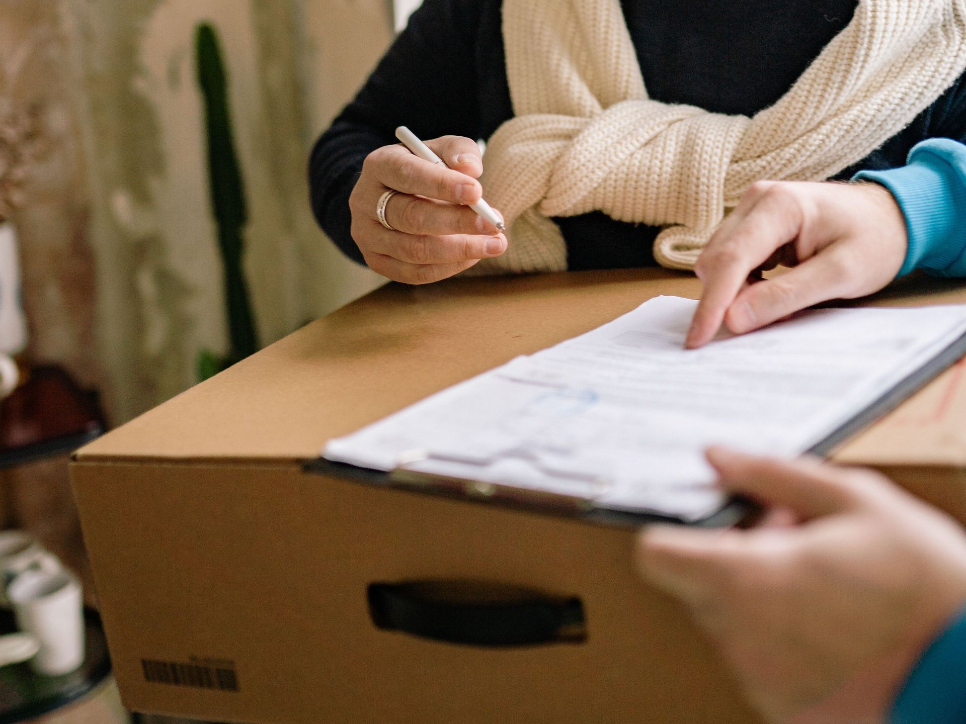 A person receives a package with a document and wears a medical mask indoors.